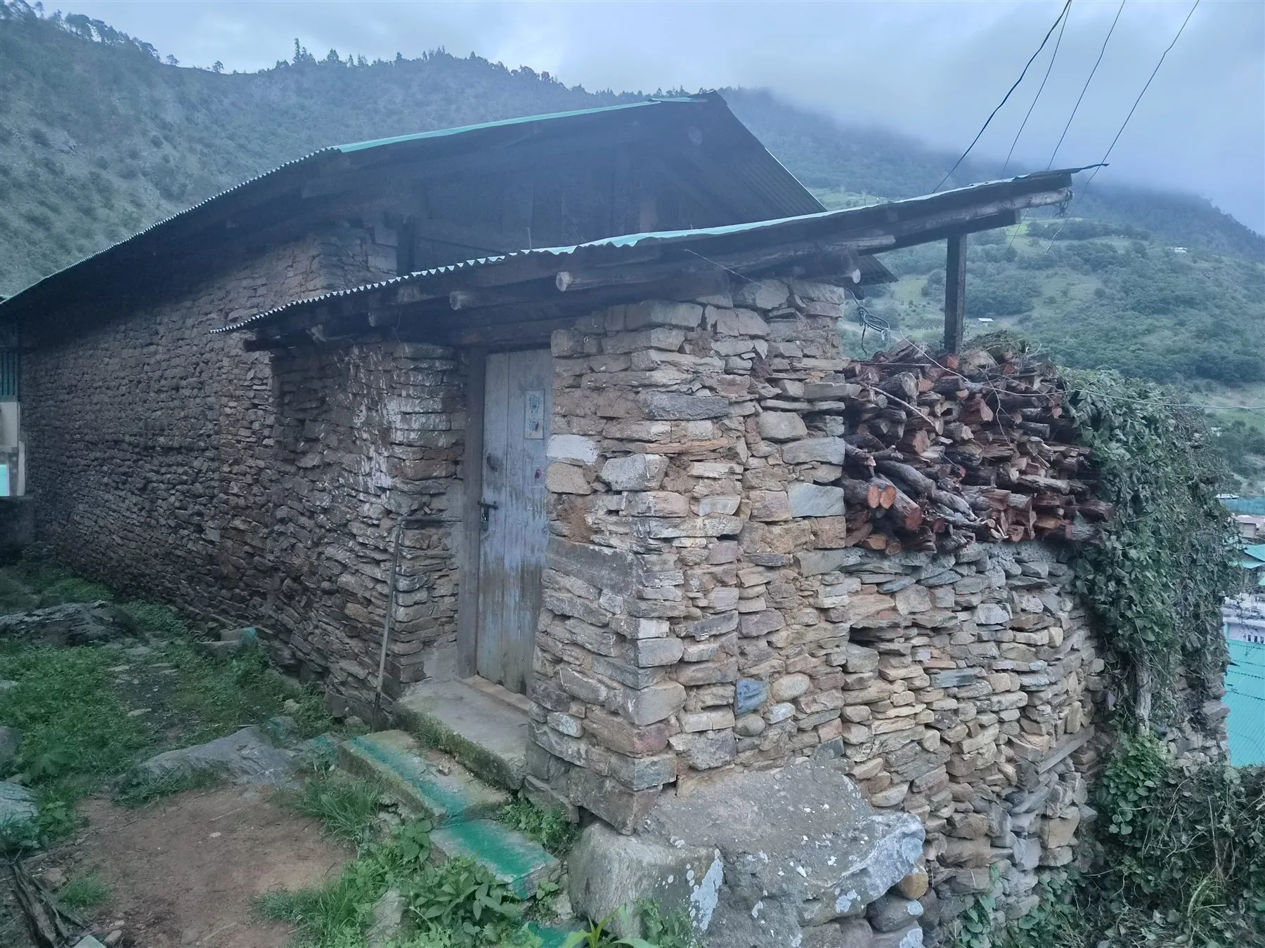 Stone walls, timber beams and stacked firewood outside the heritage village home